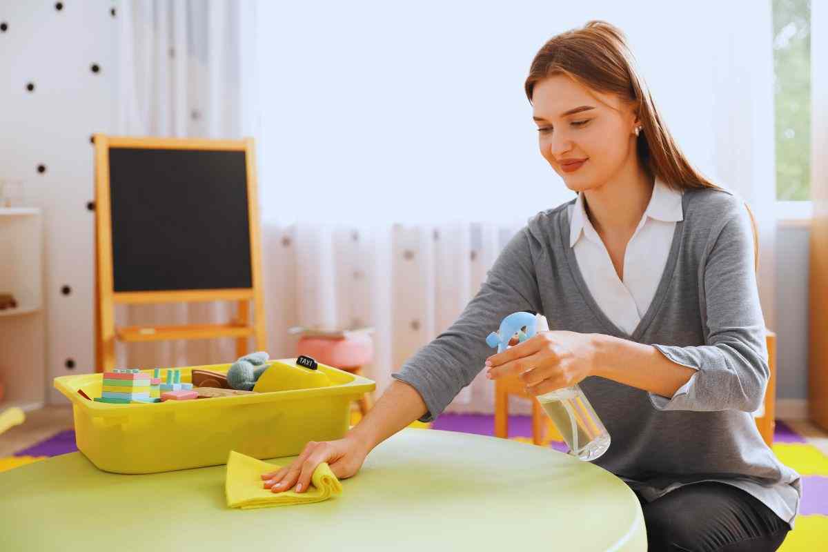 Maestra che pulisce il tavolo da gioco di un asilo