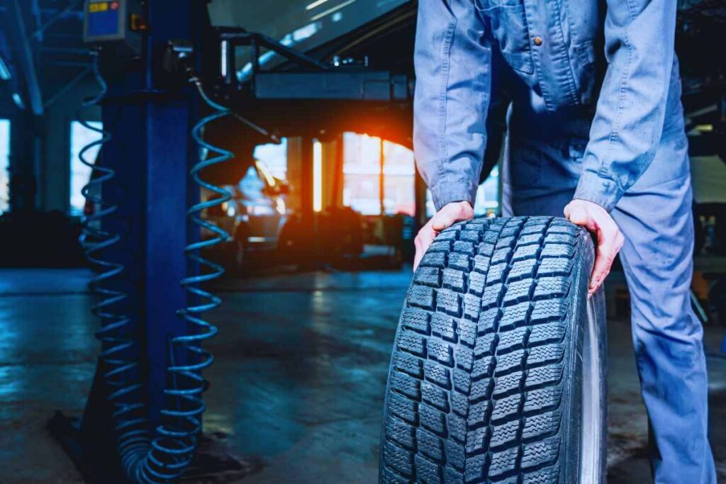 Gommista che trasporta un pneumatico in officina