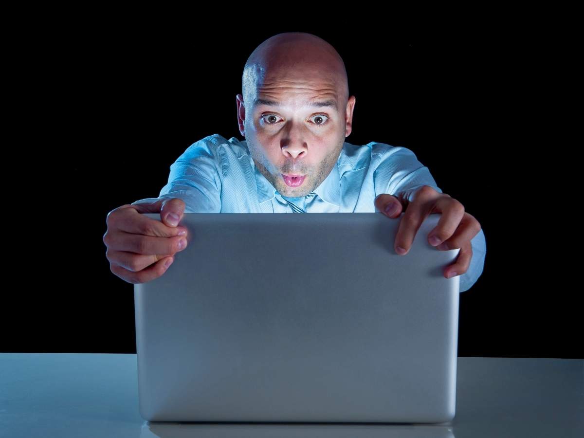 uomo che guarda foto su pc sbalordito