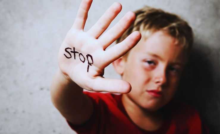 bambino con mano con scritto stop